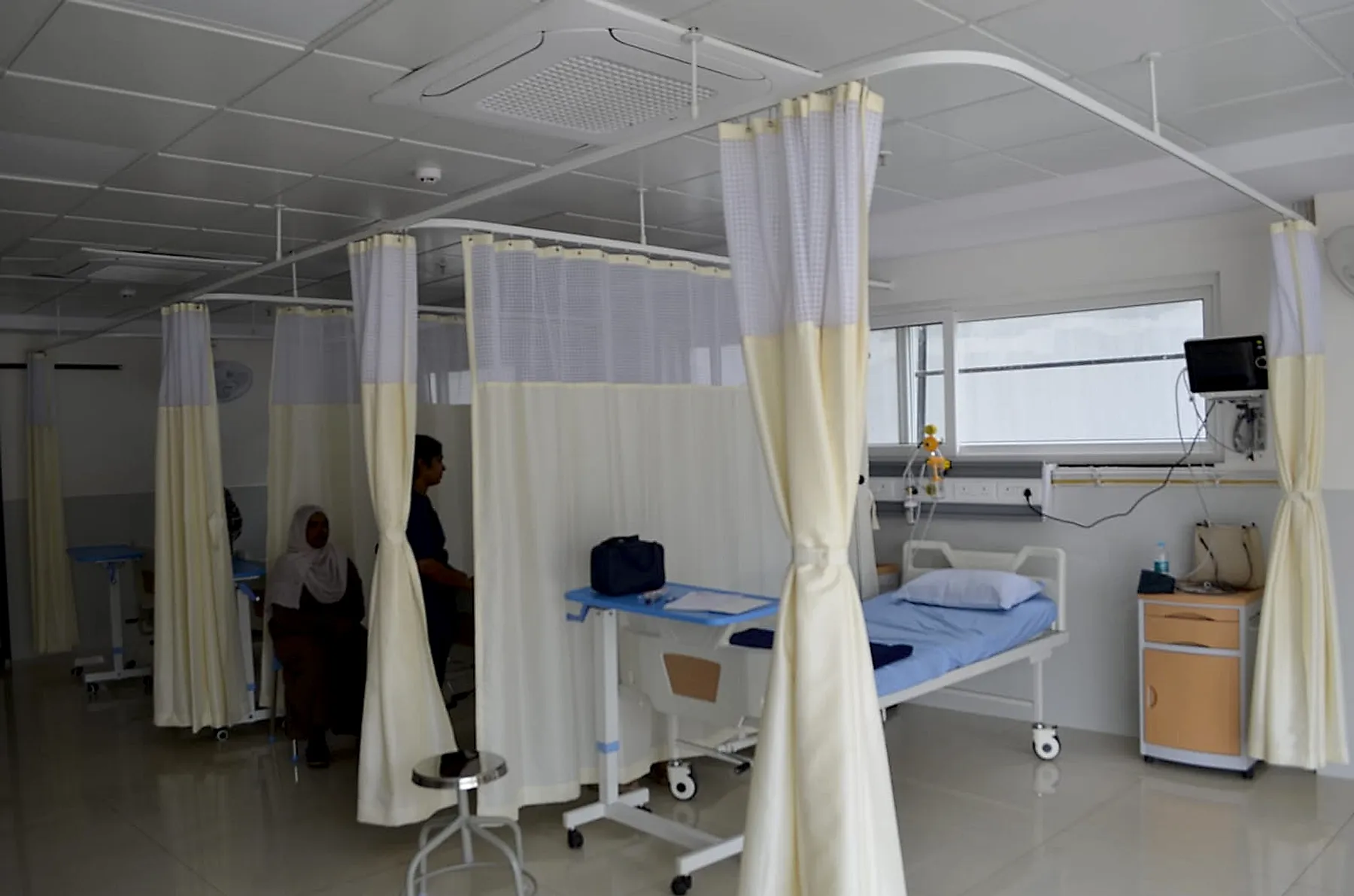 A patient's attendant seated in a curtained ward bay